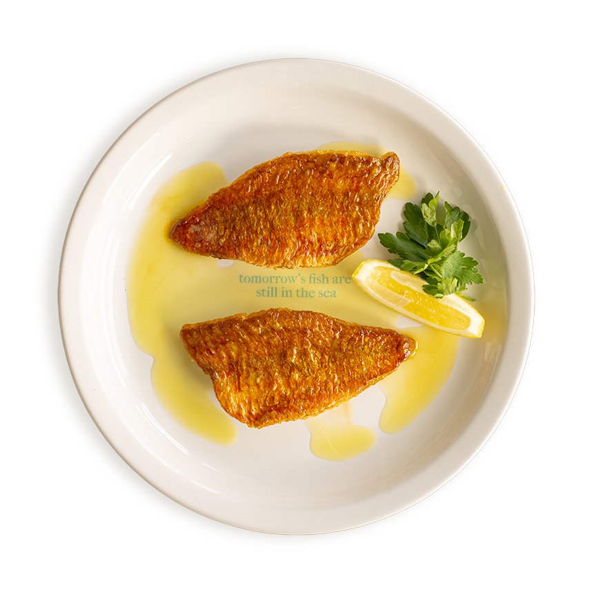 Two red mullet fillets with crispy skin, lightly oiled and served with a wedge of lemon in Rockfish restaurants