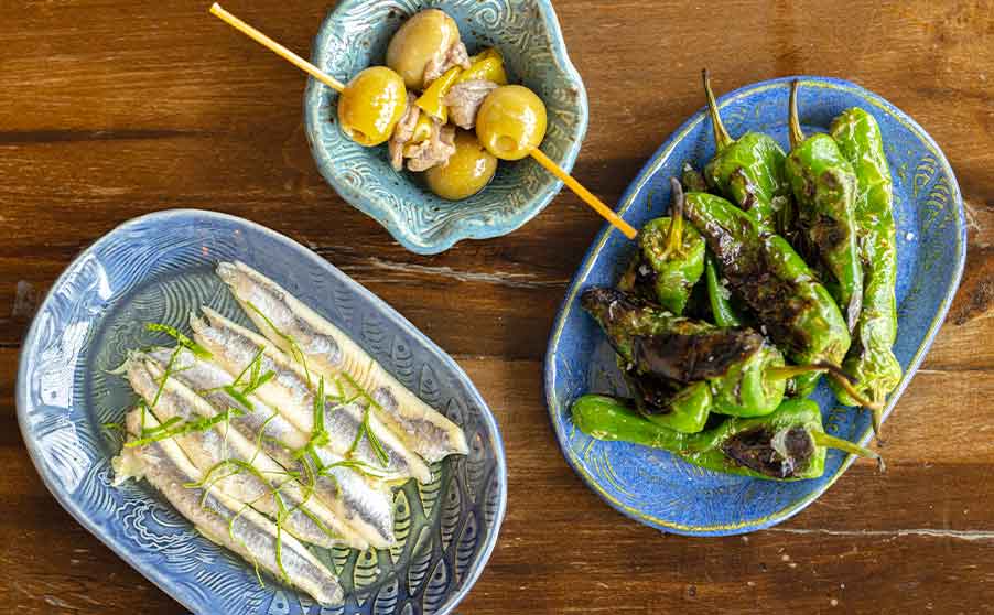 Appetisers at Rockfish on plates including, pickled anchovies, olive and anchovy skewers and guindilla peppers