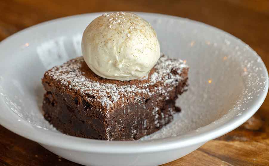 Chocolate brownie from rockfish restaurants on a plate with a scoop of ice cream on top