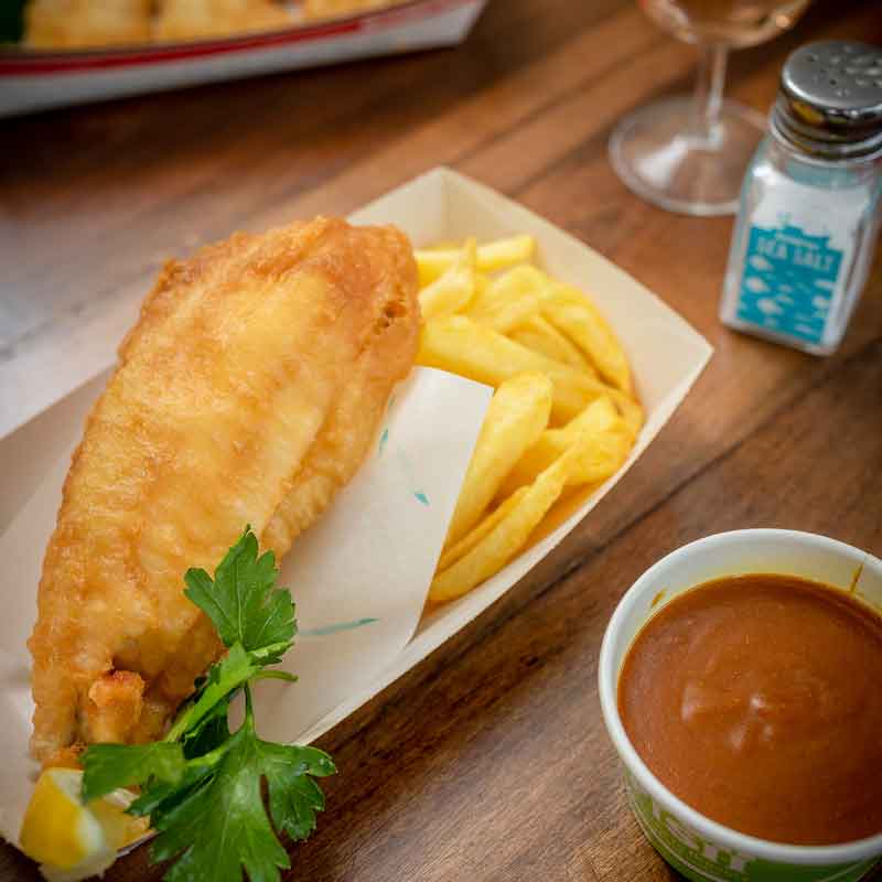 Rockfish takeaway fish & chips with a salt shaker & curry sauce on the side